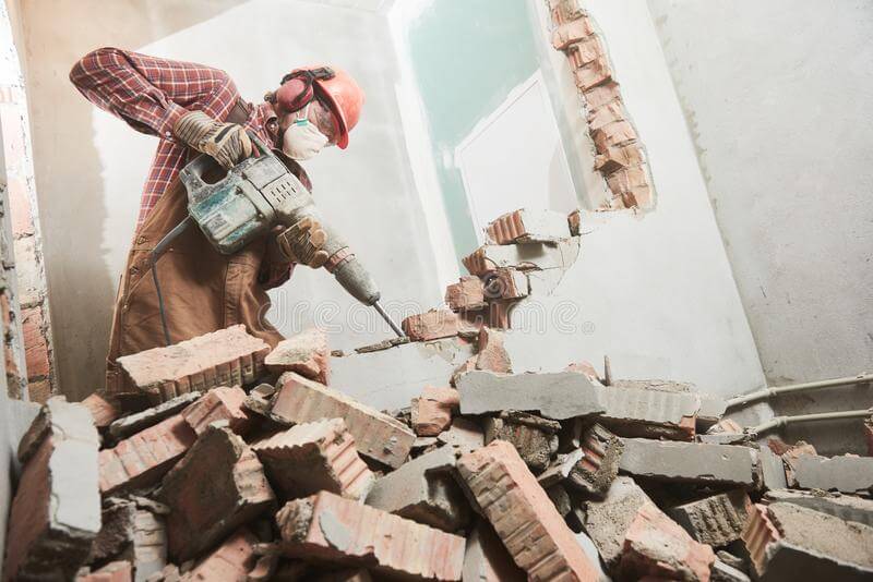 Građevinski radnik koristi Hilti bušilicu za rušenje pregradnog zida